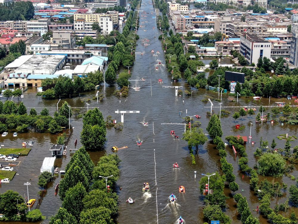 Aerial photo of a flooded intersection with cars, trees and boats after heavy rainfall