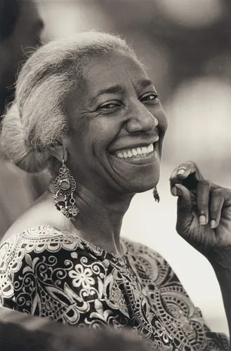 A black and white portrait of a Black woman with a smile