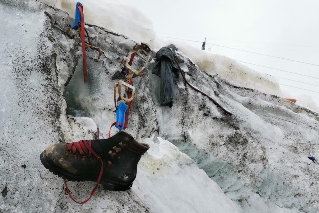 Hiking boot dangling from snow with other gear nearby