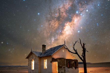 An abandoned house in the Namib Desert with the Milky Way rising above it.