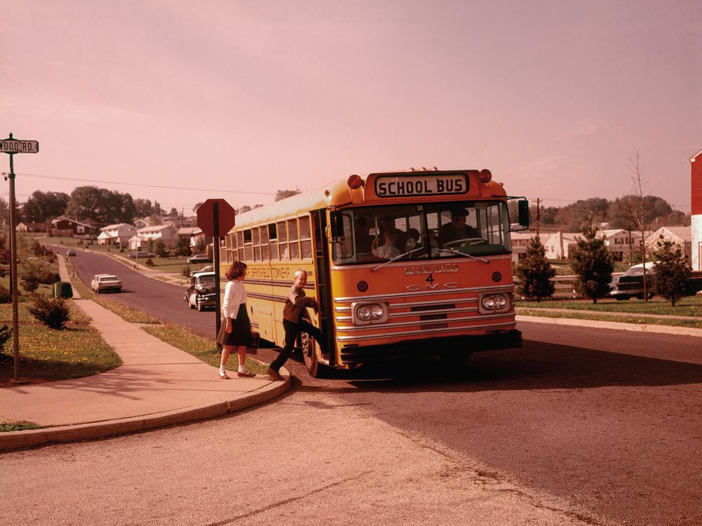 kids getting on a school bus in a suburban neighborhood in the 1960s