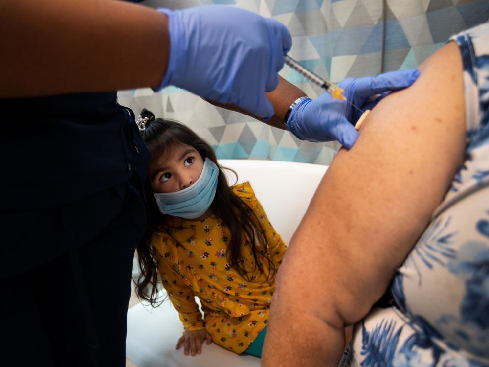 A young girl looks on as both of her grandparents are vaccinated at a clinic in Los Angeles