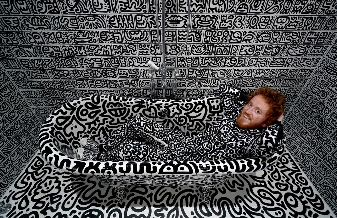 Sam Cox sitting in his doodled bathtub.