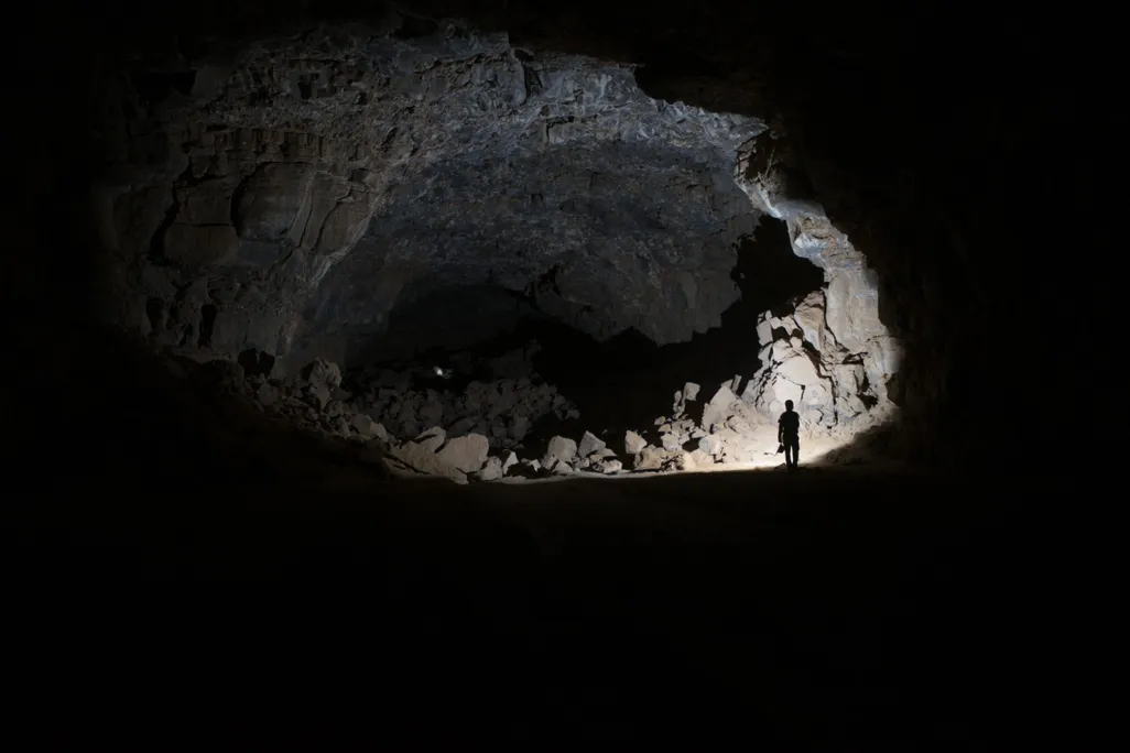 a person stands in a dimly lit cave