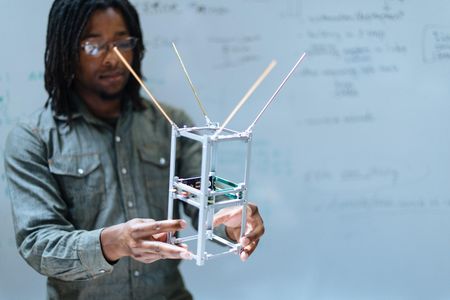 Spire’s Austin Ellis shows off a satellite frame at Spire's San Francisco headquarters. Components, like the weather sensor, stack on top of each other inside the frame. Solar panels and antennae fold out from the frame once the device is in orbit.