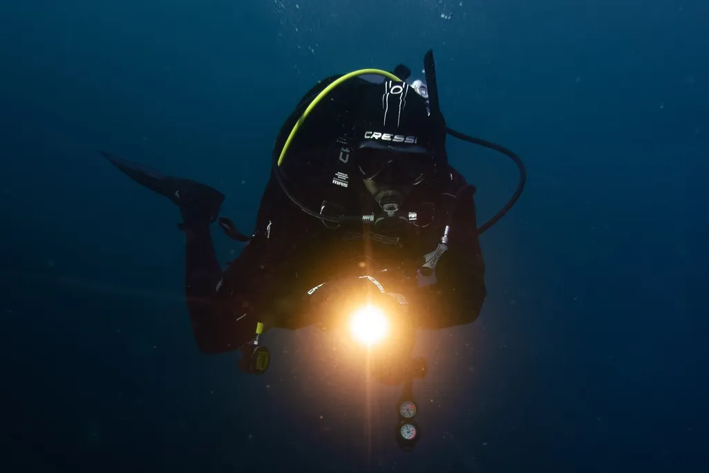 Scuba diver with a light pointing at the camera