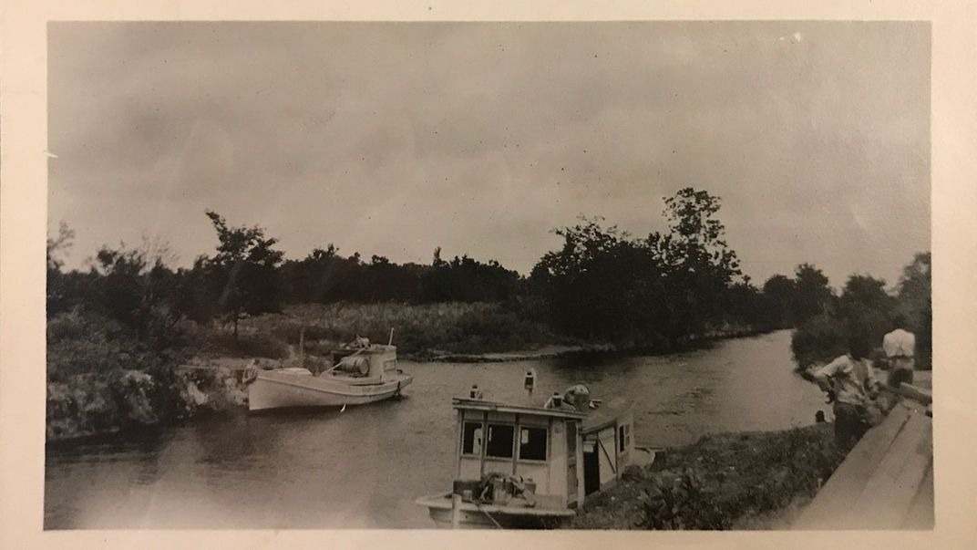 Two small boats on a narrow river. Black-and-white photo.