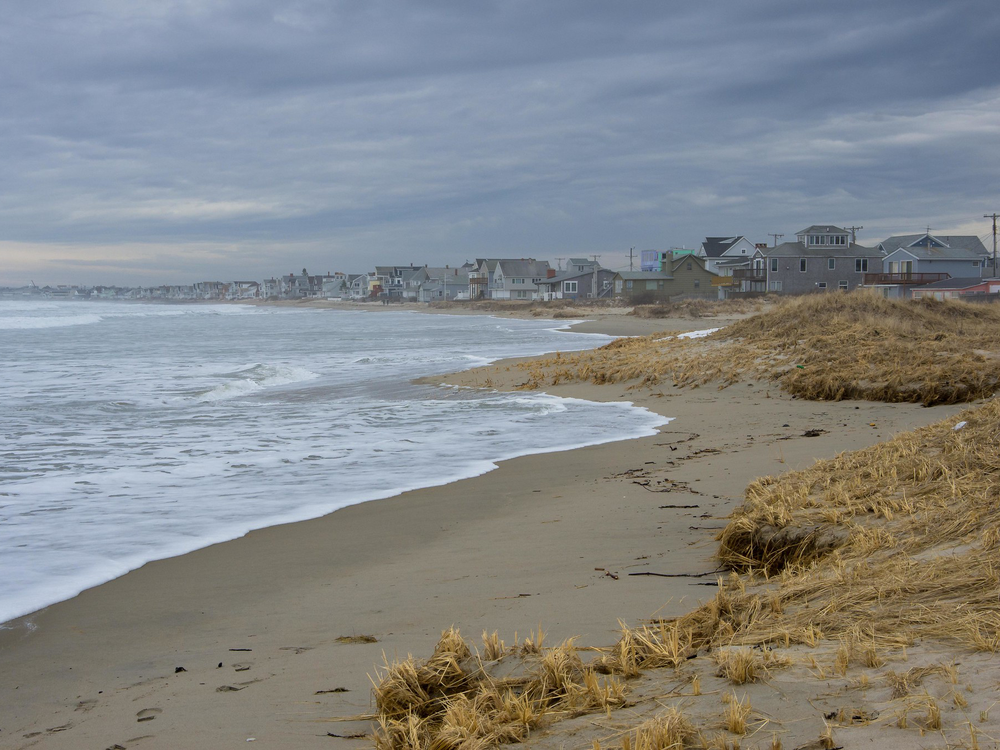 A photograph shows Wells Beach in southern Maine with beach houses on the horizon