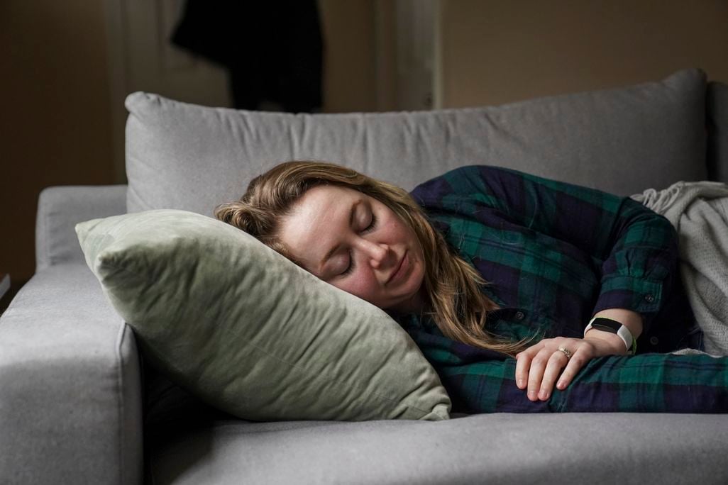 a woman lies on her side on a couch, resting on a pillow