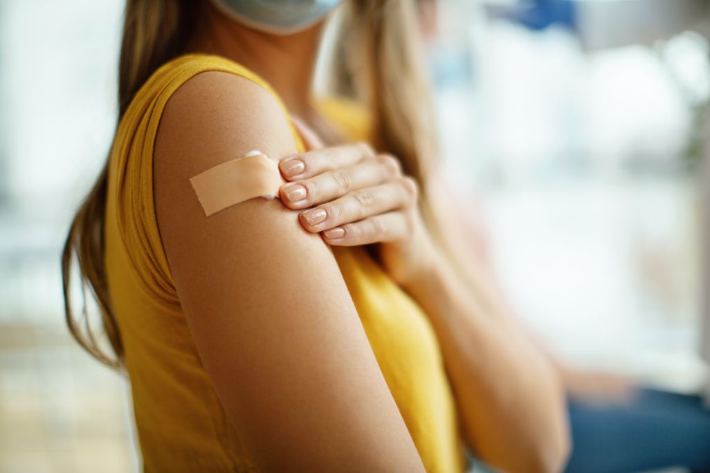 A young woman with a bandaid on her arm after getting a covid vaccine