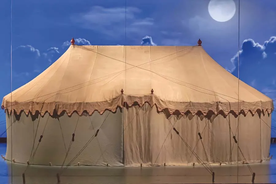 a cloth tent on display on a stage with the nigh sky projected behind it