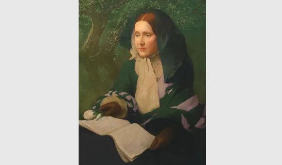 Julia Ward Howe posed seated with a book open on her lap.
