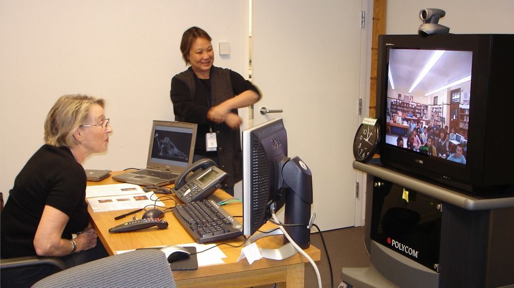 Image of two women looking at tv screen conducting a distance learning class