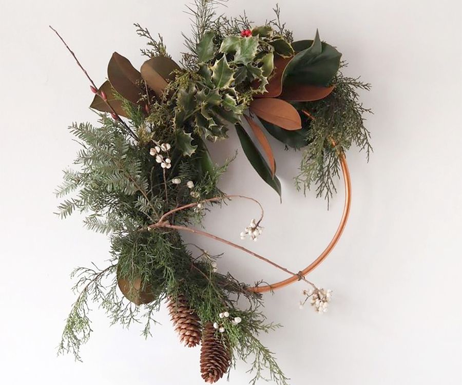 A modern evergreen wreath on a metal hoop displayed on a white background