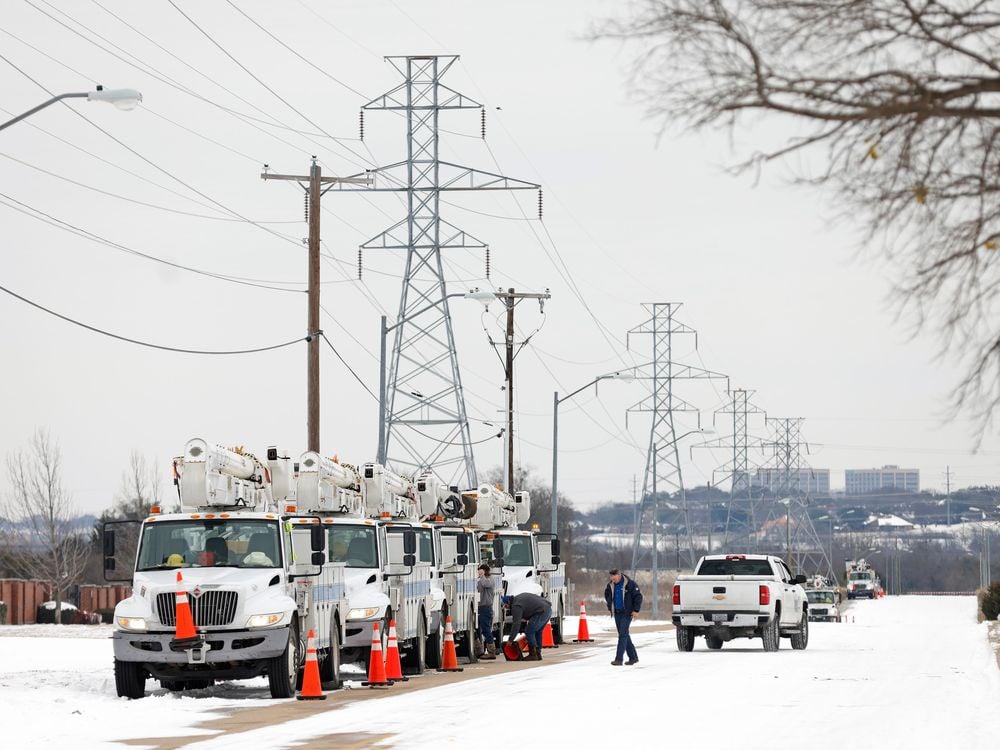 Trucks in a line under utility poles, parked on a snowy street 