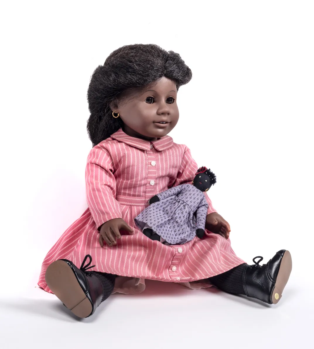 Addy Walker, a plastic doll with realistic features and hair, wears a pink dress and holds a small cloth doll of her own