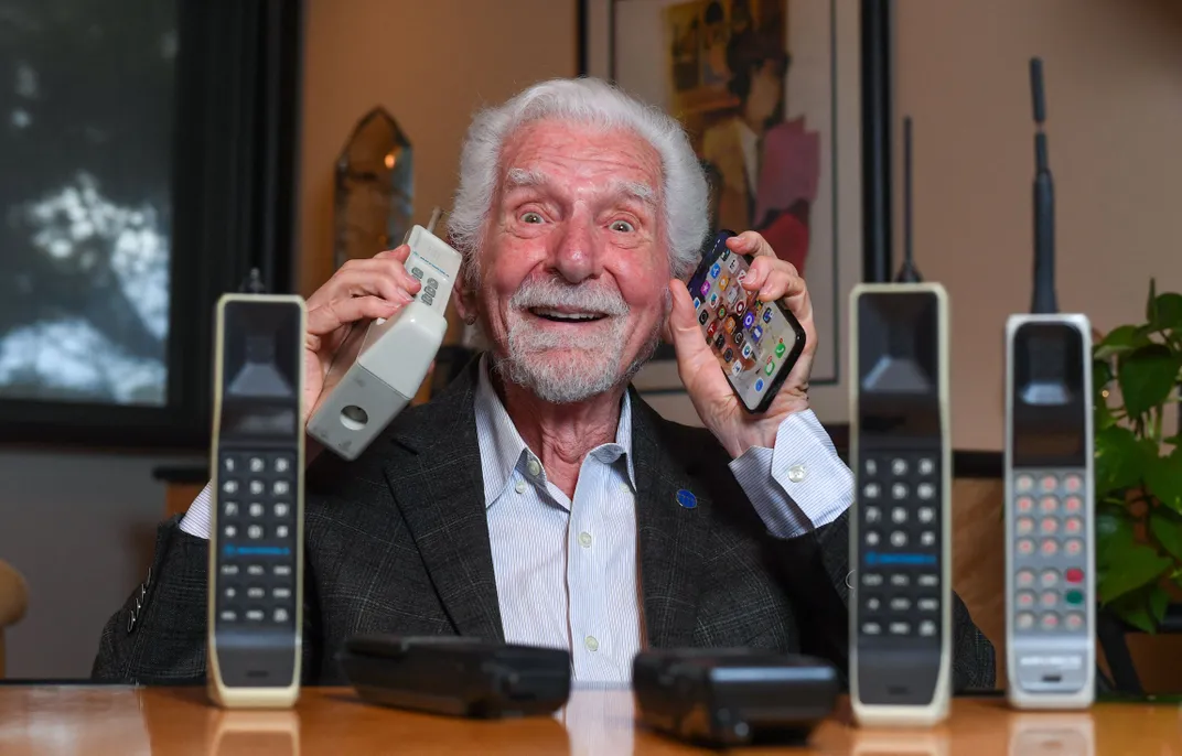 Martin Cooper with an original Motorola DynaTAC and other cell phones