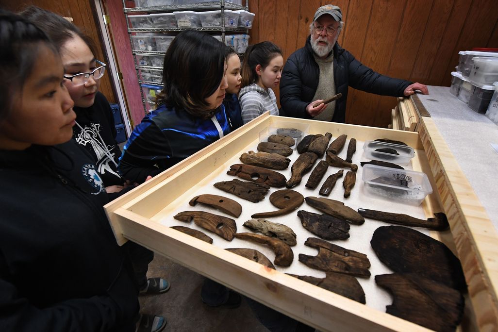 A man showing artifacts to some children at a museum