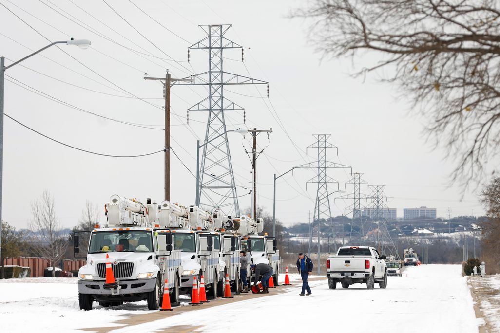 Trucks in a line under utility poles, parked on a snowy street 