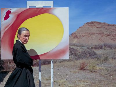 American artist Georgia O'Keeffe poses outdoors beside an easel with a canvas from her series, 'Pelvis Series Red With Yellow,' Albuquerque, New Mexico, 1960. 