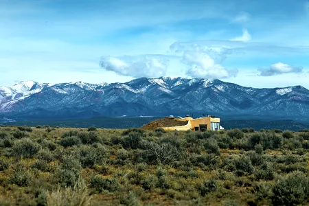 An earthship seems to rise out of the high plains at the foot of the mountains near Taos, New Mexico.