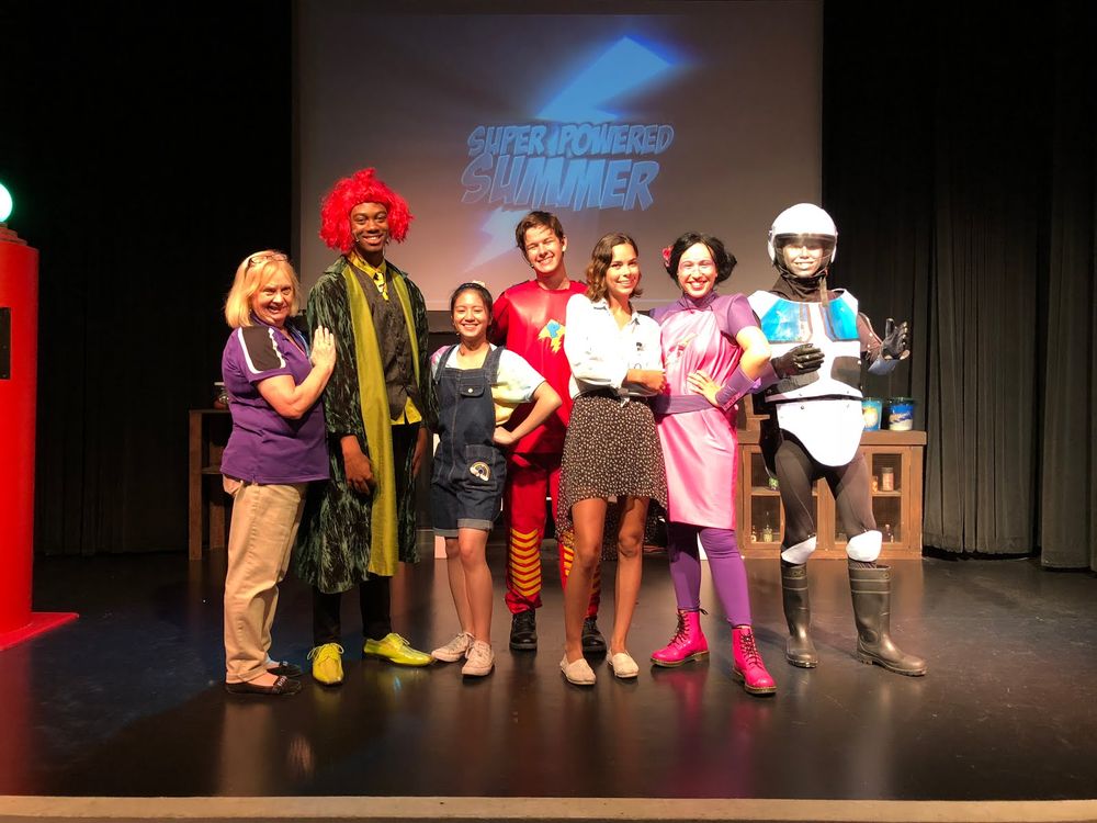 Young Ambassador, Mia Cooper and her supervisor Cathy posing with the cast of the superhero show 