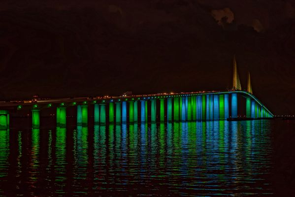 Green and blue light display illuminates Sunshine Skyway Bridge with reflection thumbnail