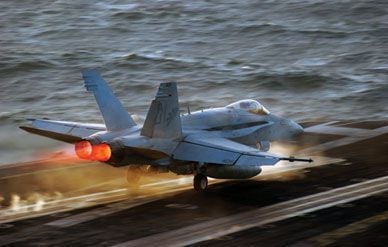 An F/A-18 Hornet lights its afterburners to leap from the deck of the aircraft carrier USS Theodore Roosevelt.