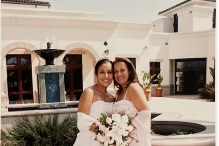 Quinceañera (fifteen-year-old girl) wearing a long strapless dress and posing by her mother's side.