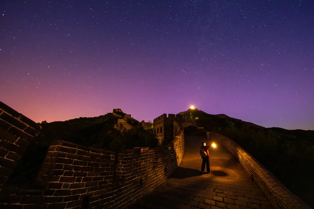 the sky appears mostly purple over the Great Wall of China, with a bit of pink and orange on the left horizon