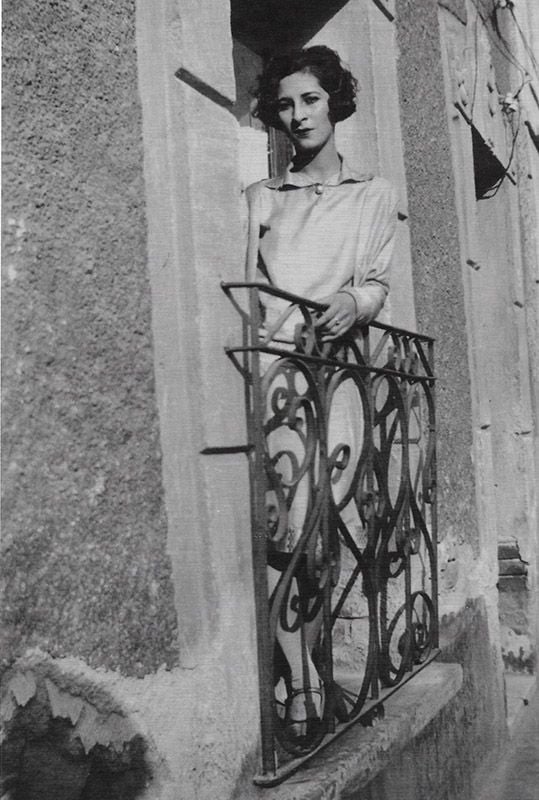 A black and white image of a woman leaning out a window