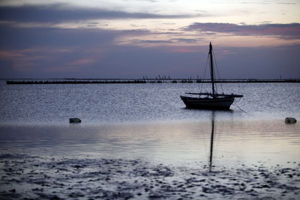 A sailboat anchored at the sea shore at sunset thumbnail