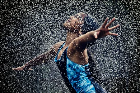 A girl runs through sprinkles of water to cool off on a hot summer day.

