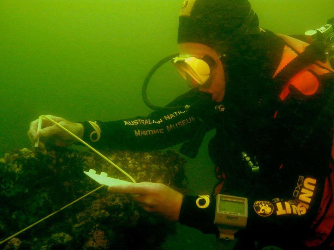 Deep sea diver examining ruins of ship