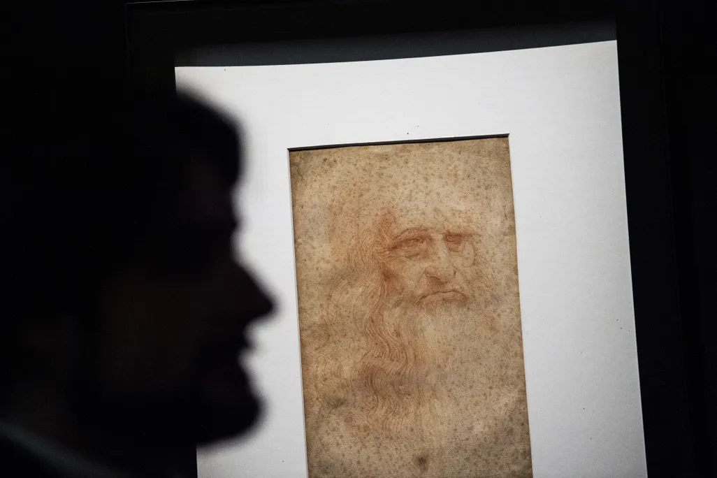A silhouette of a person's face in front of a portrait of Leonardo da Vinci