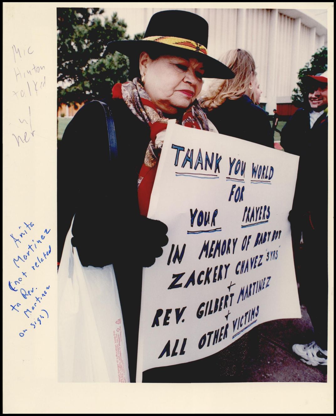 A woman in a black wide brimmed hat holds a poster in memory of the victims of the Murrah Bombing. 