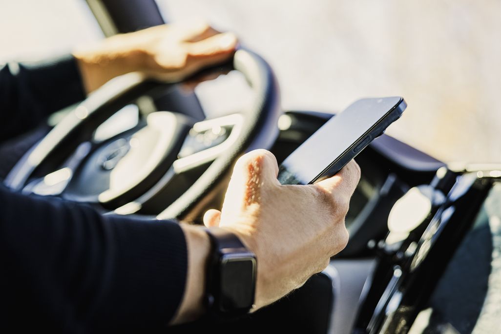 close-up of a hand holding a phone while the person is driving