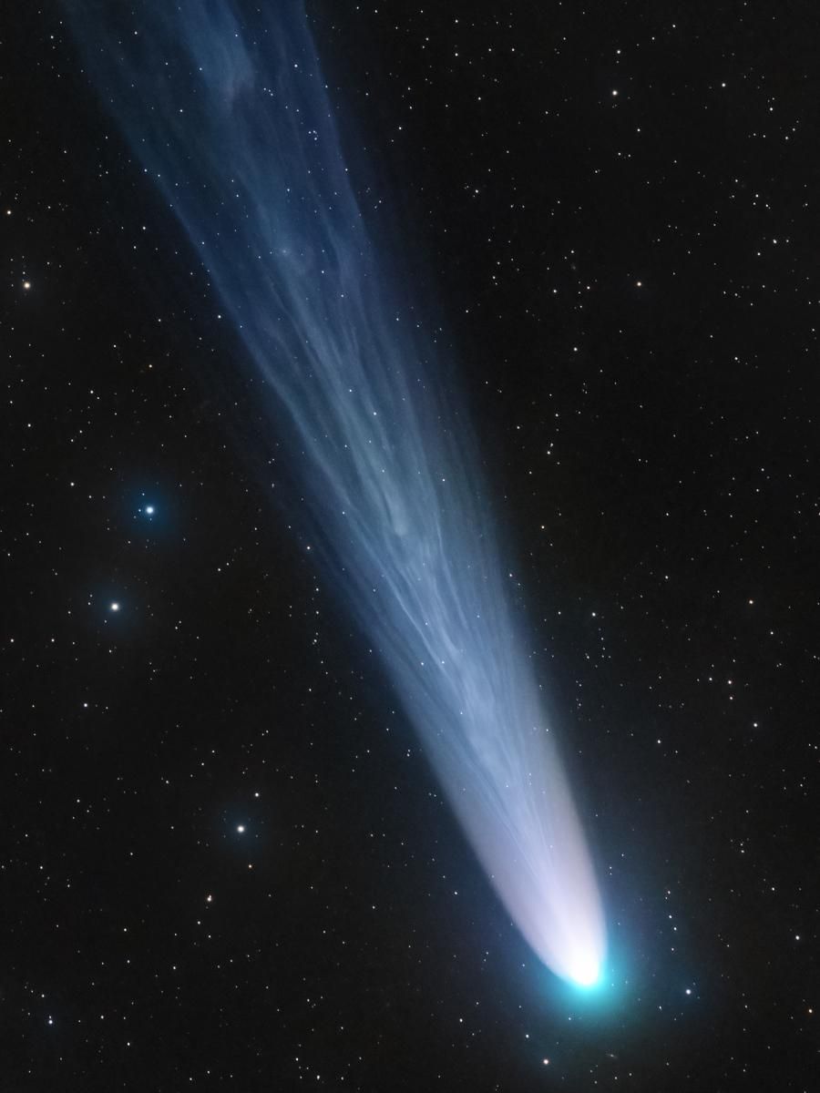 A close-up image of a falling comet. The tail is made up of silver streaks.