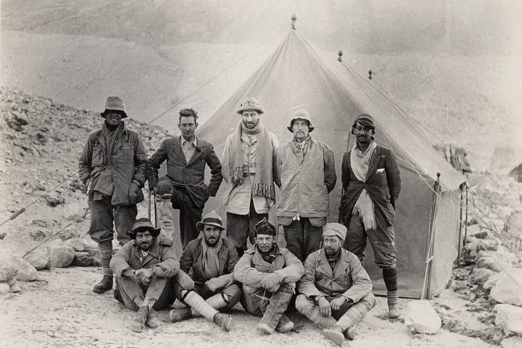 black and white photo of nine men in front of a tent