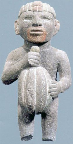 An Aztec figurine holds a cacao pod