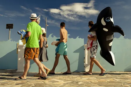 Focused on the waves, whether real or decorative, a flip-flop-wearing family&mdash;and their orca inflatable&mdash;heads to the beach.