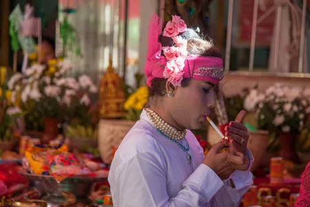 A spirit medium pauses to light a cigarette.