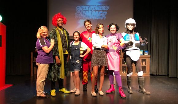 Young Ambassador, Mia Cooper and her supervisor Cathy posing with the cast of the superhero show 