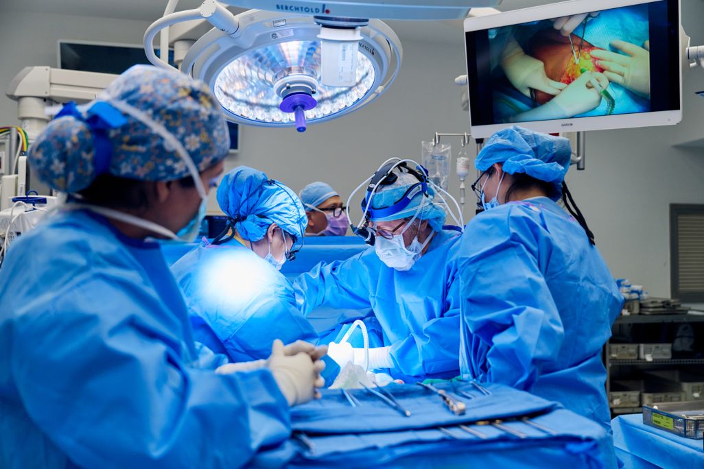 Surgeons in an operating room wearing blue scrubs working on a patient