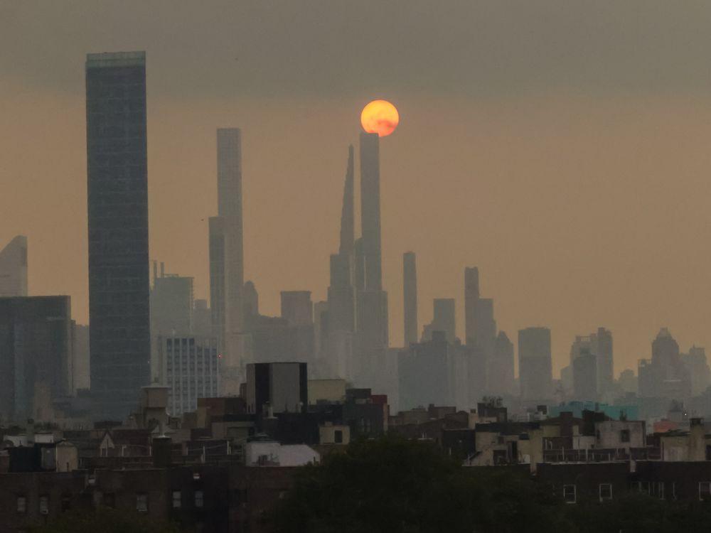 A photograph of the New York City skyline showing hazy air and the sun in the background