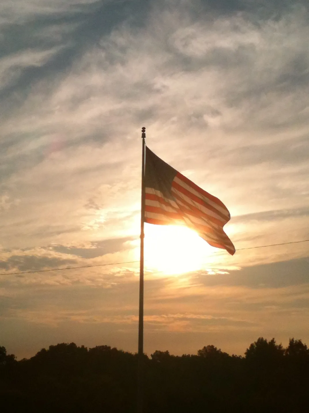 Capturing the sun rise behind the American Flag at my daughters grave ...