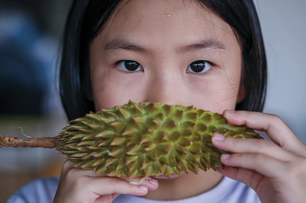 a child drinking water from the durian’s outer shell.