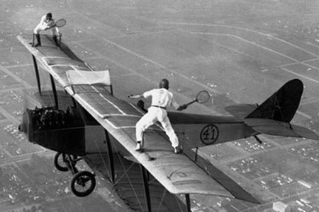 Gladys Roy and Ivan Unger play tennis on the wing of a biplane in flight, 1925.