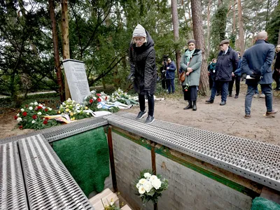 A woman throws flowers on the boxes containing human remains at Waldfriedhof cemetery.