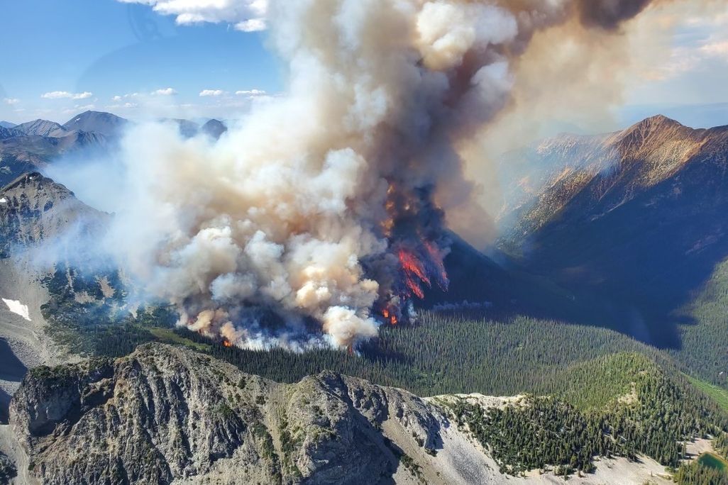 An aerial view of smoke rising from a wildfire on a mountain